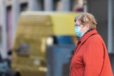 Viyana, Avusturya - 04 Nisan 2020: Yaşlı kadın sokakta maske takıyor, Corona virüsü enfeksiyonuna karşı korunuyor, baharın güneşli bir gününde alışveriş yapıyor