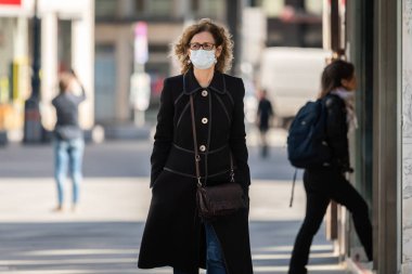 Viyana, Avusturya - 04 Nisan 2020: Yaşlı kadın sokakta maske takıyor, Corona virüsü enfeksiyonuna karşı korunuyor, baharın güneşli bir gününde alışveriş yapıyor