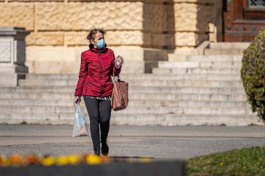 Viyana, Avusturya - 04 Nisan 2020: Yaşlı kadın sokakta maske takıyor, Corona virüsü enfeksiyonuna karşı korunuyor, baharın güneşli bir gününde alışveriş yapıyor