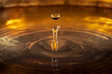 Yüzeye vuran su damlacıklarının yakın plan, koyu, bronz arkaplan