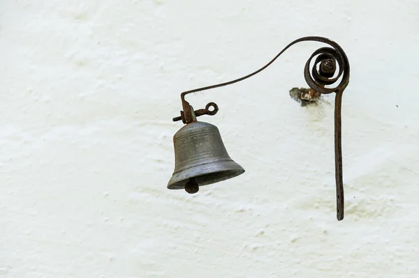 白い壁に掛かっている青銅製の古い小さな鐘の閉鎖 — ストック写真