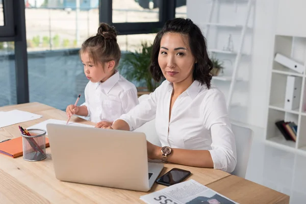 Aziatische zakenvrouw met dochter in kantoor — Stockfoto