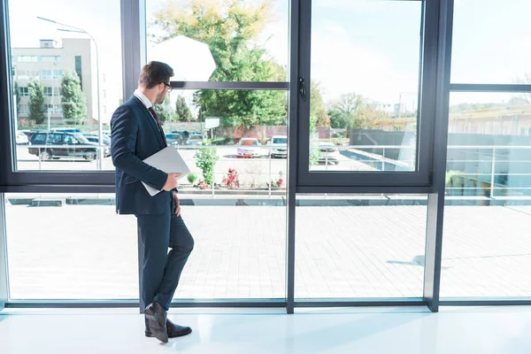 Businessman holding laptop in office — Stock Photo, Image