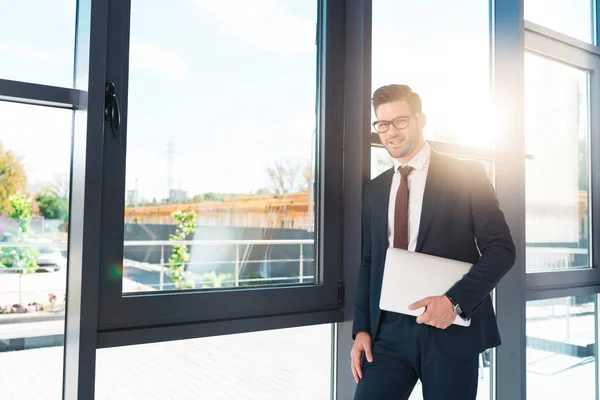 Businessman holding laptop in office — Stock Photo, Image