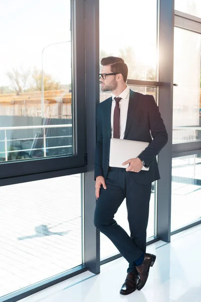 Businessman holding laptop in office — Stock Photo, Image