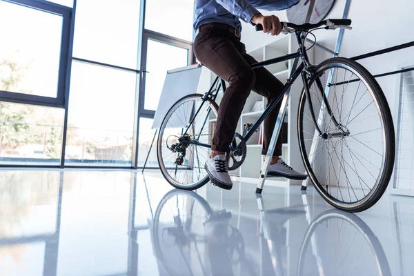 Businessman with bicycle in office — Stock Photo, Image