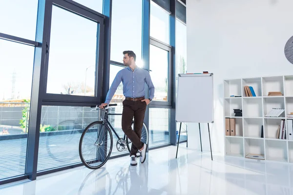 Empresário com bicicleta no escritório — Fotografia de Stock