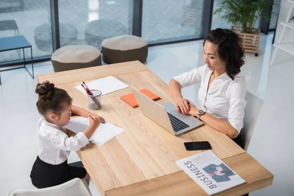 Asian businesswoman with daughter in office — Stock Photo
