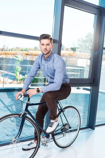 Молодий бізнесмен з велосипедом в офісі — стокове фото
