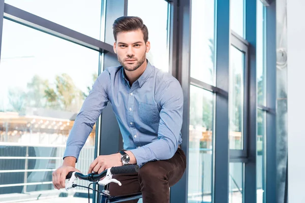 Jovem empresário com bicicleta no escritório — Fotografia de Stock