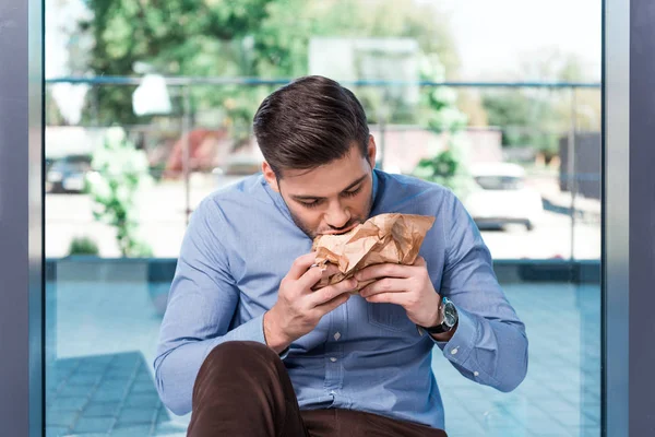 Businessman eating hamburger — Stock Photo