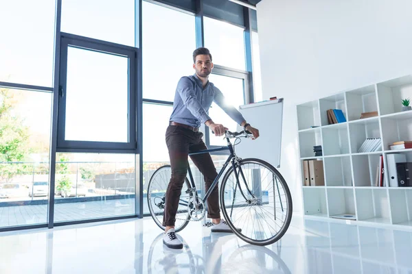 Empresário com bicicleta no escritório — Fotografia de Stock
