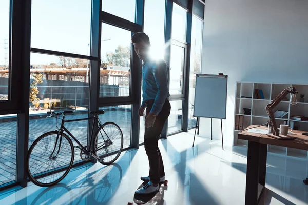 Businessman on skateboard in office — Stock Photo