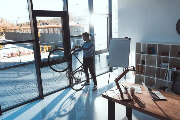 Businessman with bicycle in office — Stock Photo