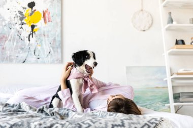 Pijama siyah beyaz köpek yavrusu ile birlikte yatakta yatan genç kadın