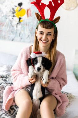 baş ve santa şapka içinde köpek yavrusu üzerinde geyik ile gülümseyen kadın portresi boynuzları 