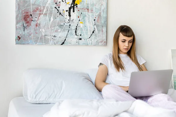 Wanita Muda Terfokus Menggunakan Laptop Saat Beristirahat Tempat Tidur Pagi — Foto Stok Gratis