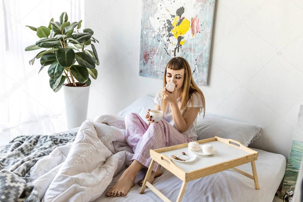 young woman with cup of coffee and zephyr in morning at home