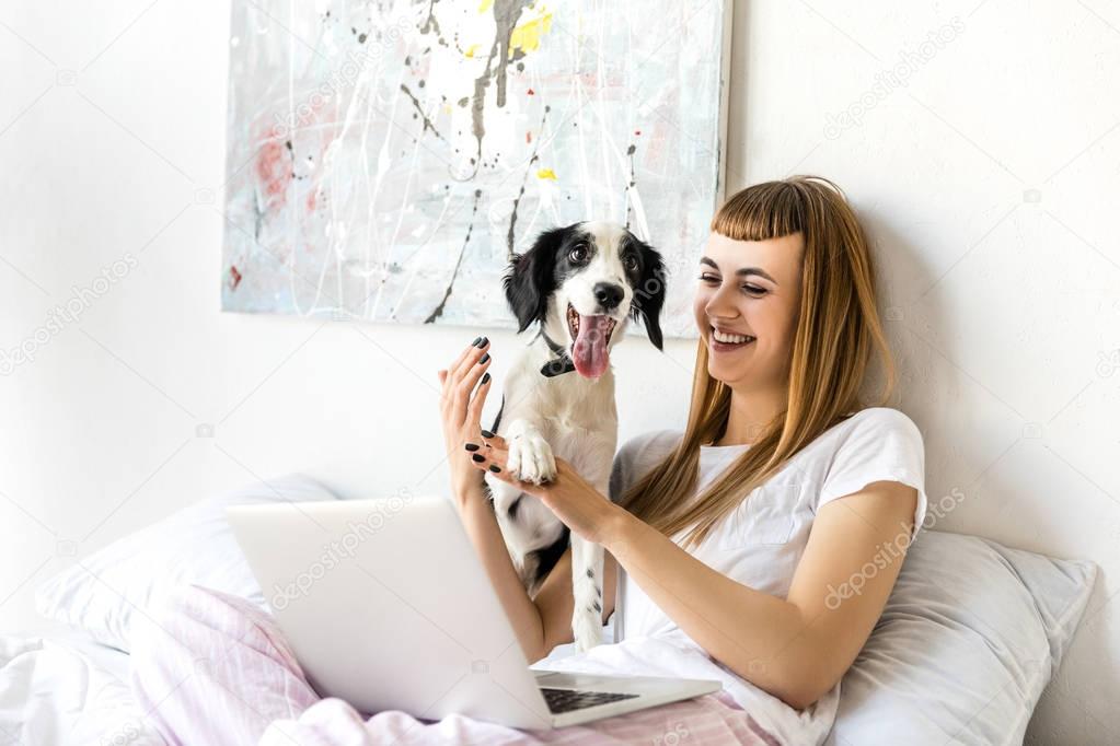 portrait of happy woman playing with puppy in morning at home
