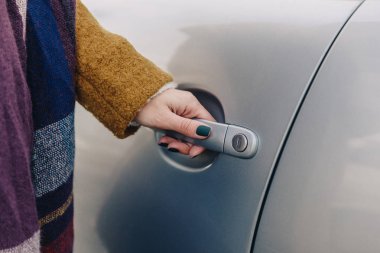 partial view of woman holding car door handle clipart