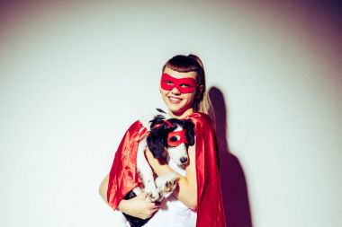 portrait of smiling woman holding puppy in superhero costume clipart