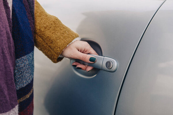 partial view of woman holding car door handle