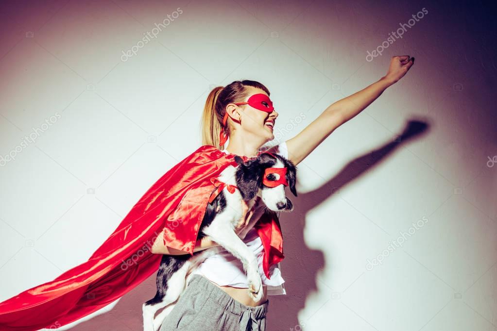 side view of smiling woman and little puppy in superhero costumes