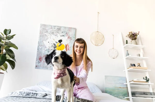 Selective focus of cheerful woman in pajamas and cute puppy on bed in morning at home — Stock Photo