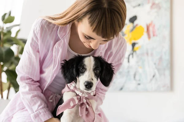 Портрет женщины в пижаме и милый маленький щенок утром дома — стоковое фото