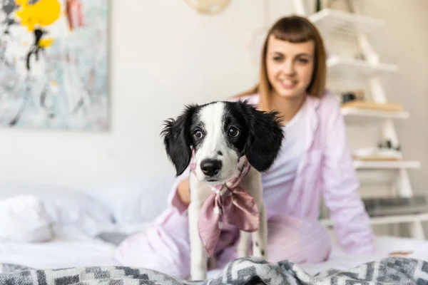 Foco seletivo de mulher sorridente em pijama e filhote de cachorro adorável na cama em casa — Fotografia de Stock