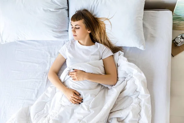 Overhead view of young woman sleeping in bed in morning — Stock Photo