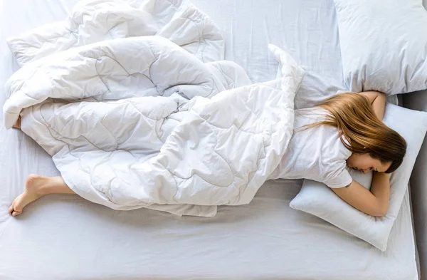 Overhead view of young woman sleeping in bed in morning — Stock Photo