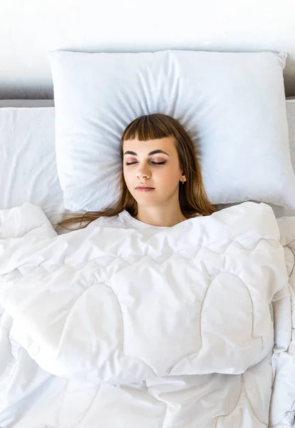 Overhead view of young woman sleeping in bed in morning — Stock Photo