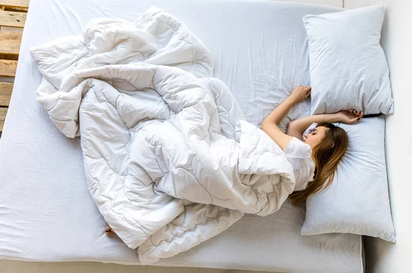 Overhead view of young woman sleeping in bed in morning — Stock Photo