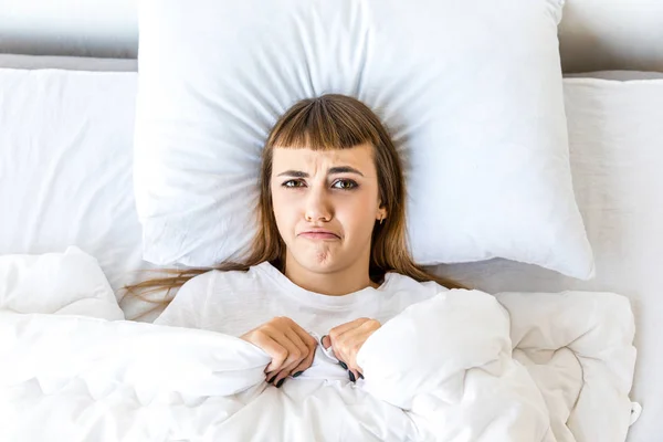 Вид грустной женщины, смотрящей в камеру во время отдыха в постели по утрам — стоковое фото