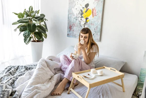 Jovem com xícara de café e zephyr de manhã em casa — Fotografia de Stock