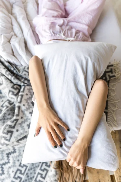 Visão obscurecida da mulher abraçando travesseiro enquanto deitado na cama — Fotografia de Stock