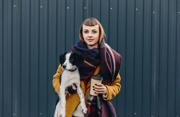 Retrato de jovem segurando cachorro e café para ir em mãos enquanto em pé na rua — Fotografia de Stock