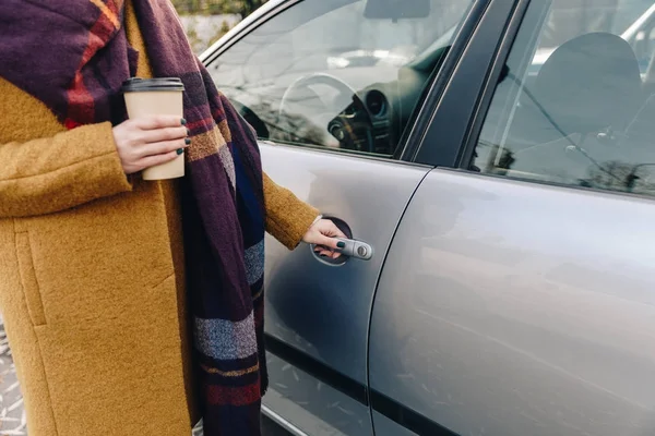 Visão parcial da mulher com café para ir na mão segurando maçaneta da porta do carro — Fotografia de Stock