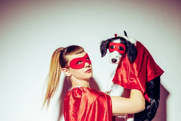 Vista lateral de la joven mujer y el cachorro en trajes de superhéroe - foto de stock