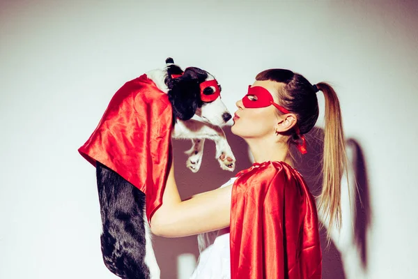 Vista laterale della donna baciare cucciolo in costume da supereroe — Foto stock