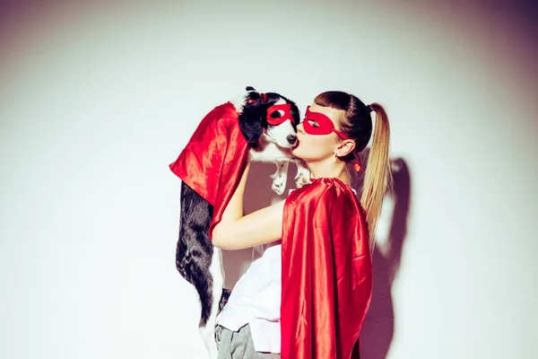 Вид сбоку женщины, целующей щенка в костюме супергероя — стоковое фото