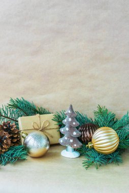 Noel ağacı oyuncakları, kozalaklar ve el sanatları kağıdının üzerindeki çam dalları, üstünde ve altında yazılı metinler olan bir tebrik kartı şeklinde.