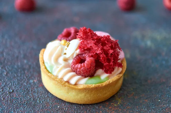 Homemade muffin with sweet cream and fresh raspberries on a gray blurry background close up