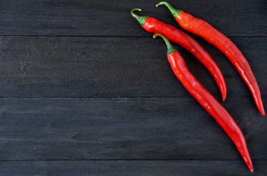 Üstten Görünüm üzerinde üç kırmızı sıcak biber kopya alanı siyah ahşap zemin üzerinde. Üstten Görünüm