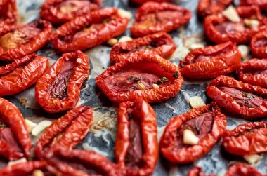 Birçok baharat karanlık bir yüzeyi ile kırmızı domates Kurutulmuş. Kurutulmuş domates doku arka plan yakın çekim