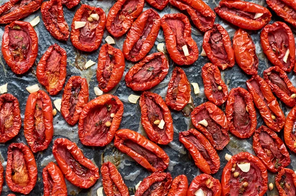 Muchos tomates rojos secos con especias en una superficie oscura. Tomates secos textura fondo — Foto de Stock