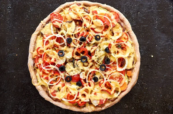 Pizza vegetariana caliente con tomates, pimiento, cebolla, aceitunas negras, queso, especias sobre fondo negro oscuro de cerca — Foto de Stock