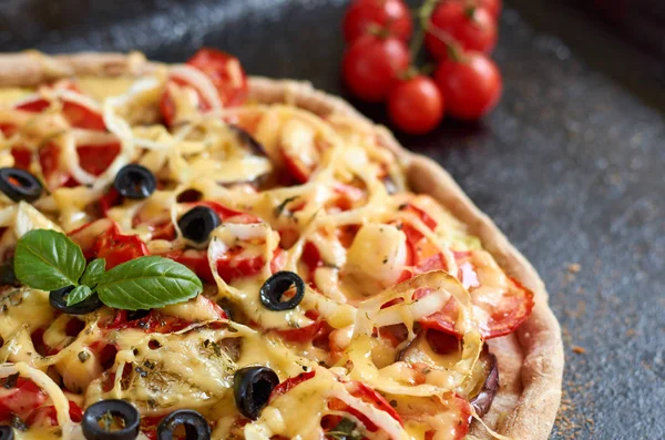 Pizza vegetariana caliente con tomates, pimiento, cebolla, aceitunas negras, queso, especias sobre fondo de bandeja de hornear negro oscuro decorado con tomates cherry pequeños cerca con espacio para copiar — Foto de Stock