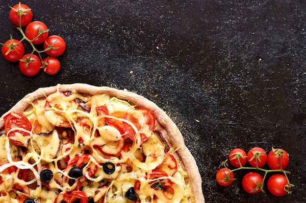 Pizza vegetariana caliente con tomates, pimiento, cebolla, aceitunas negras, queso, especias sobre fondo de bandeja de hornear negro oscuro decorado con tomates cherry pequeños cerca con espacio para copiar — Foto de Stock